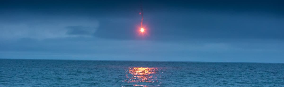 Red distress flare burning over open water — Comet manufacturer photograph