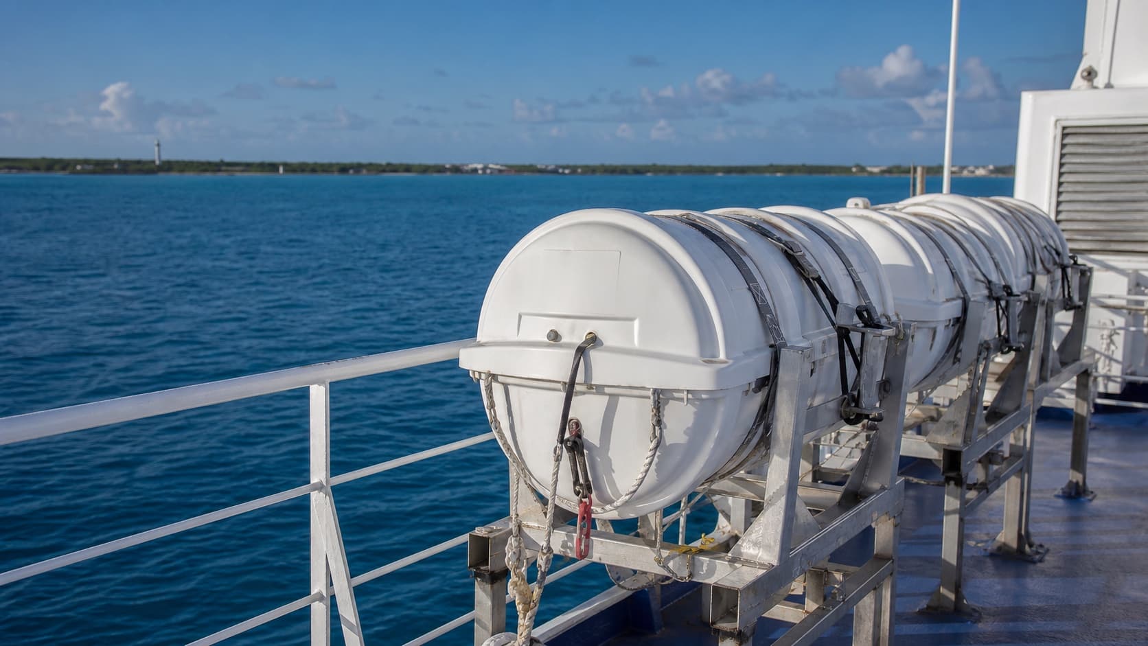 Enclosed liferaft canisters secured on a vessel with open water behind them