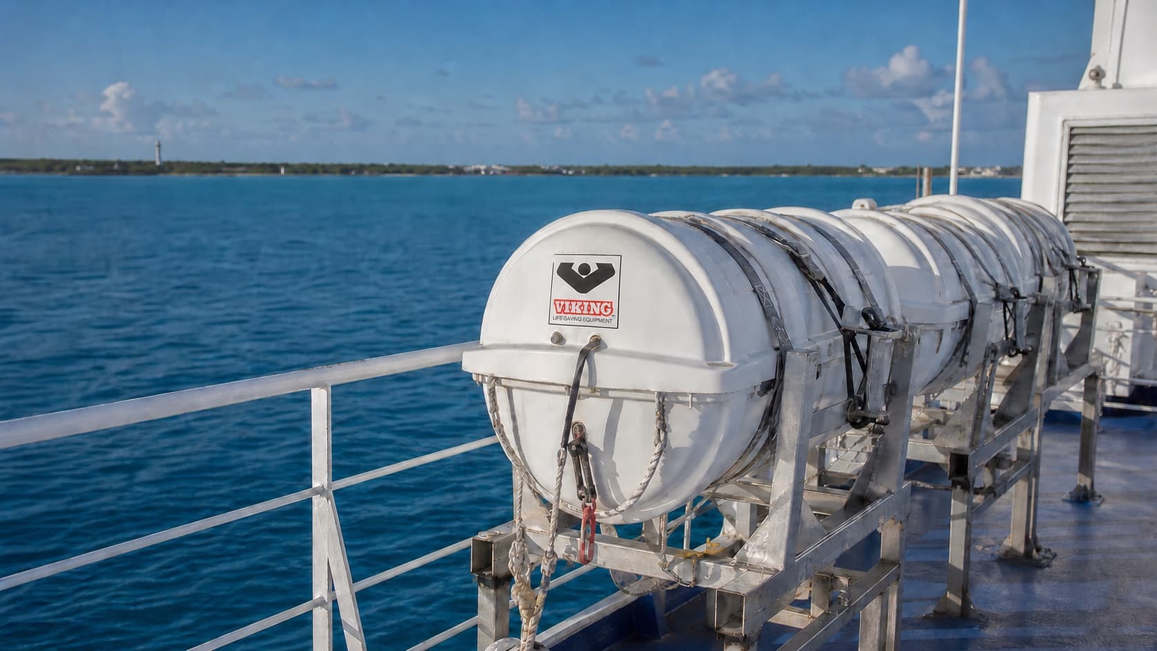 Enclosed liferaft canisters secured on a vessel with open water behind them