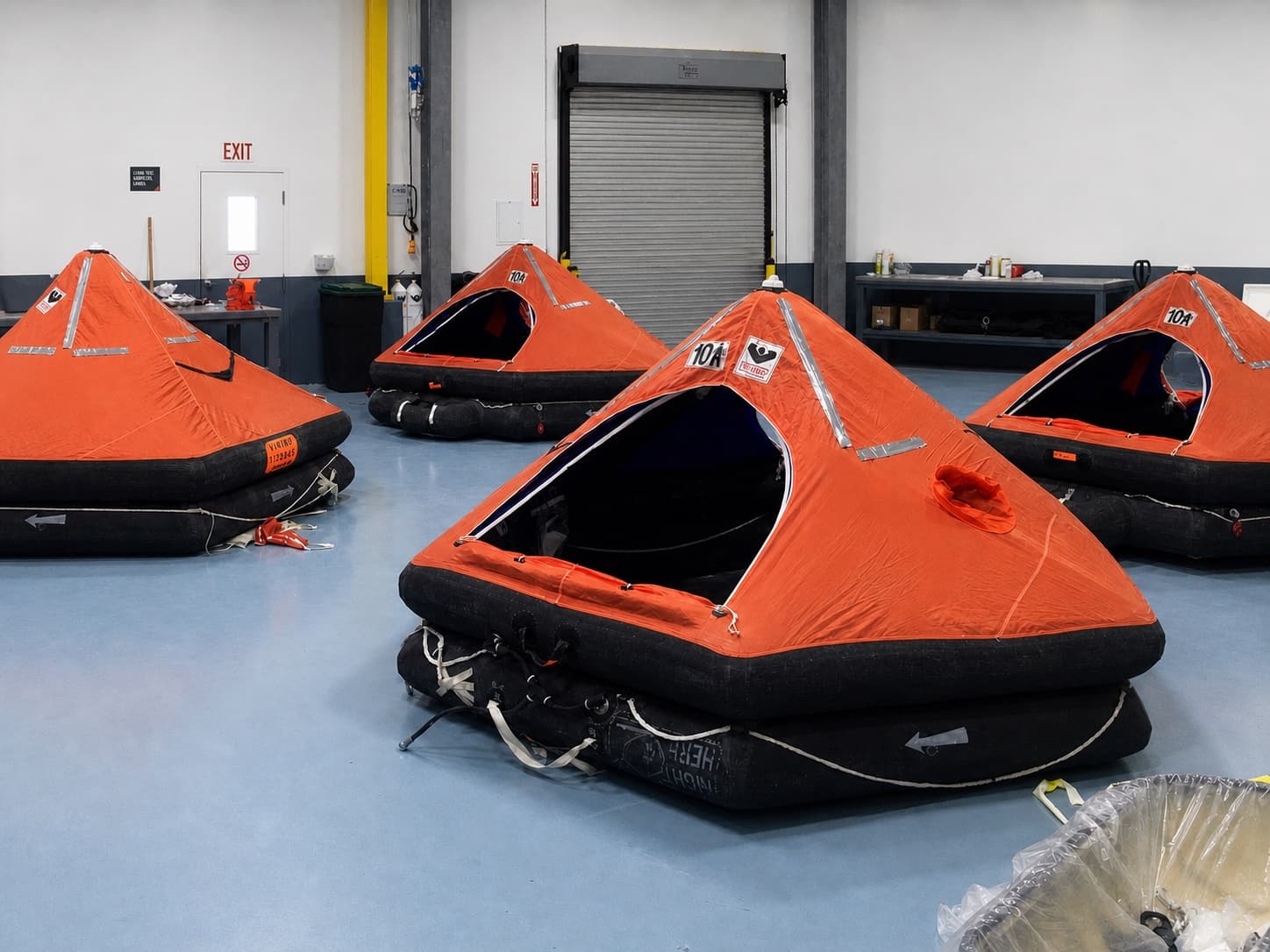 Four open liferafts arranged across The Safety Pelican workshop floor