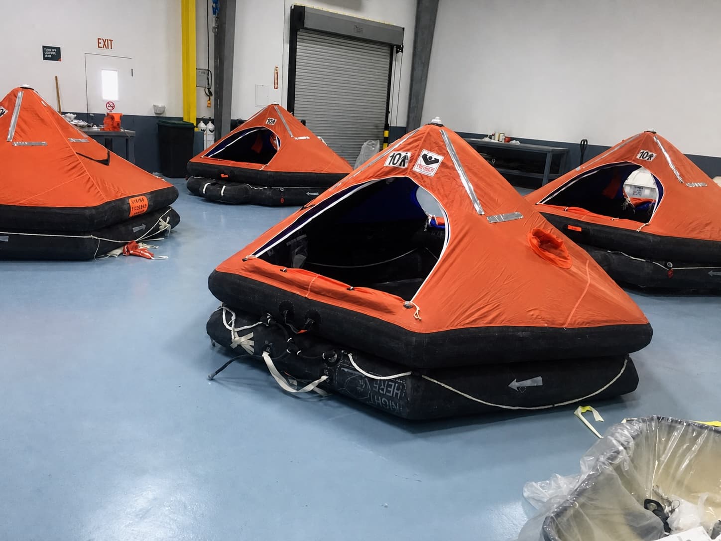 Four open liferafts arranged across The Safety Pelican workshop floor